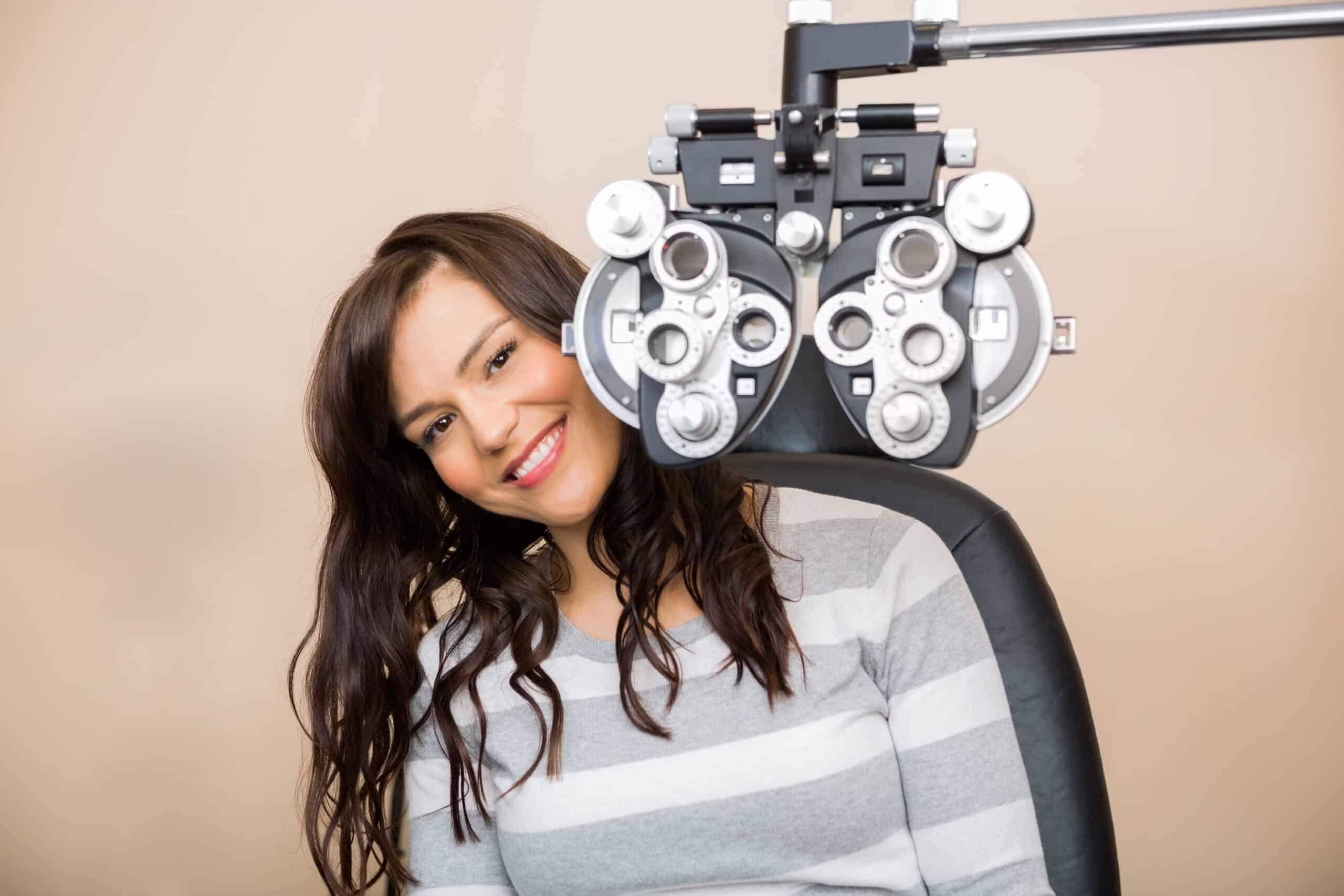 Woman sitting behind a phoropter during an eye exam