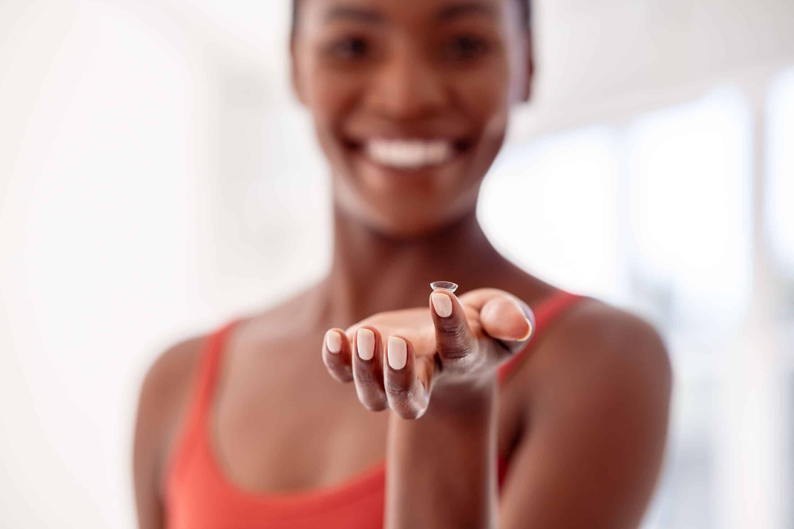 Woman with a contact lens on her finger tip